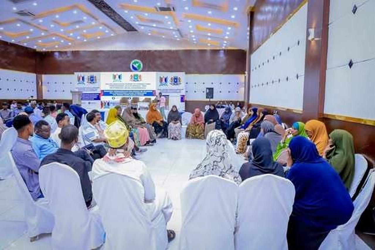 A large hall filled with participants seated at round tables during a dialogue forum.